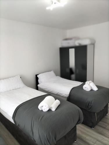 2 letti con asciugamani in una stanza di Remaj Service Accommodation, Sleep 7 a Dagenham