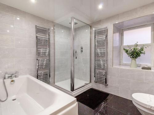 a bathroom with a shower and a tub and a sink at Queen Victoria Suite in Stanhope