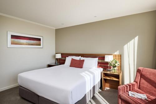 a bedroom with a white bed and a red chair at View Melbourne in Melbourne