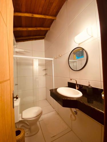 a bathroom with a toilet and a sink and a mirror at Maui Suítes e Chalés in Arraial d'Ajuda
