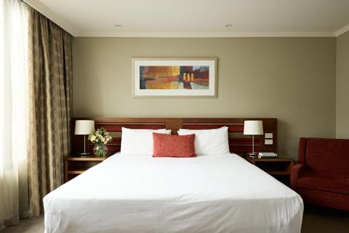 a bedroom with a white bed and a red chair at View Melbourne in Melbourne