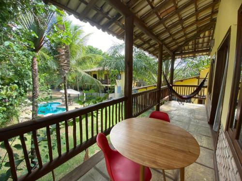 a table and chairs on a balcony with a view of a pool at Maui Suítes e Chalés in Arraial d'Ajuda