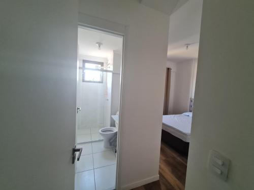 een open deur naar een badkamer met een toilet en een bed bij Apartamento na Praia Martim de Sá com linda vista in Caraguatatuba