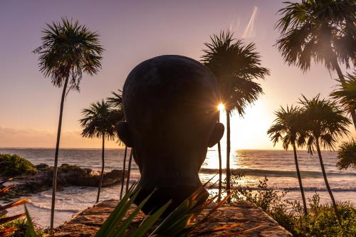 a statue of a head on a beach with palm trees at Diamante K - Inside Tulum National Park in Tulum