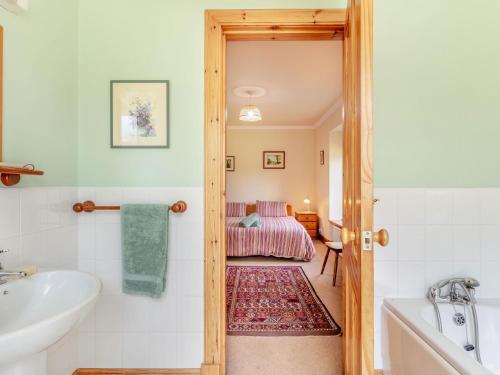a bathroom with a tub and a sink and a bed at The Old Laundry in Grantown on Spey