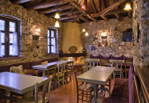 a restaurant with tables and chairs and a stone wall at Virginia in Asprangeloi