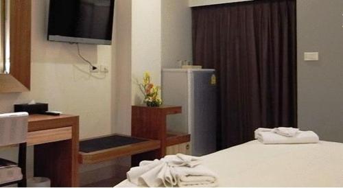 a room with a bed and a desk and a refrigerator at April Suites in Pattaya Central