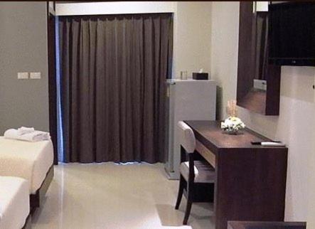 a room with a desk and a room with a bed and a table at April Suites in Pattaya Central