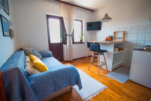 uma sala de estar com um sofá azul e uma cozinha em Apartments by the sea Maslinica, Solta - 776 em Grohote