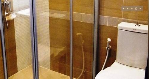 La salle de bains est pourvue d'une douche en verre et de toilettes. dans l'établissement April Suites, à Pattaya
