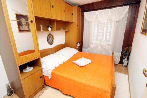 a small bedroom with an orange bed and a window at Apartments by the sea Pucisca, Brac - 770 in Pučišća