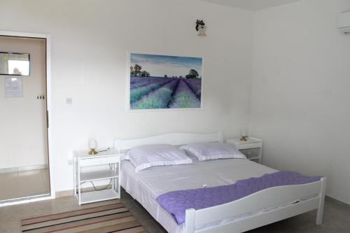 a white bedroom with a bed and two white tables at Apartments by the sea Mimice, Omis - 656 in Mimice