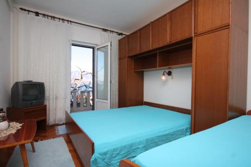 a bedroom with two beds and a tv and a window at Apartments by the sea Postira, Brac - 740 in Postira