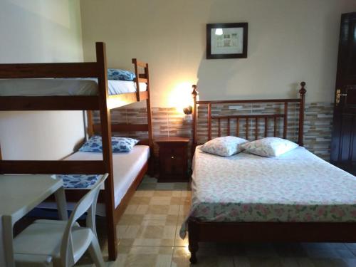 a bedroom with two bunk beds and a desk at Pousada da Geisa in Bertioga