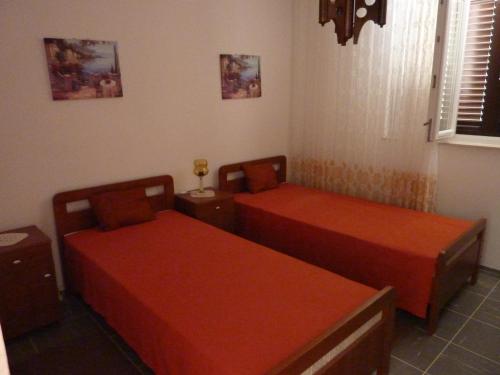 two beds in a room with red sheets at Apartments by the sea Seget Vranjica, Trogir - 976 in Seget Vranjica