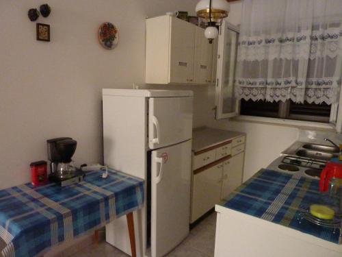 a small kitchen with a white refrigerator and a table at Apartments by the sea Seget Vranjica, Trogir - 976 in Seget Vranjica