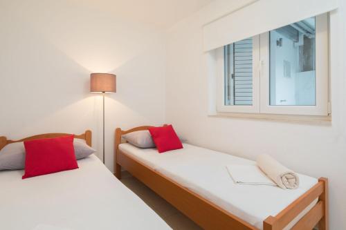 two twin beds in a room with a window at Apartments by the sea Seget Vranjica, Trogir - 978 in Seget Vranjica