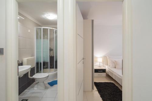a white bathroom with a toilet and a sink at Apartments by the sea Seget Vranjica, Trogir - 978 in Seget Vranjica