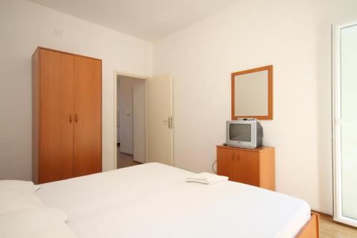 - une chambre avec un lit blanc et une télévision dans l'établissement Apartment Lucica 990b, à Lastovo