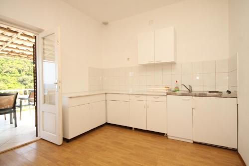a white kitchen with white cabinets and a table at Apartments and rooms by the sea Lucica, Lastovo - 990 in Lastovo