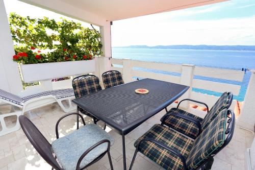 een tafel en stoelen op een balkon met uitzicht op de oceaan bij Apartments by the sea Pisak, Omis - 1014 in Pisak