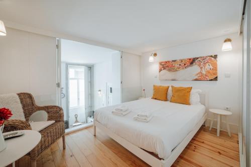 1 dormitorio blanco con 1 cama y 1 silla en Historic & Sunny Mezzanine Bolhão by Vacationy, en Oporto