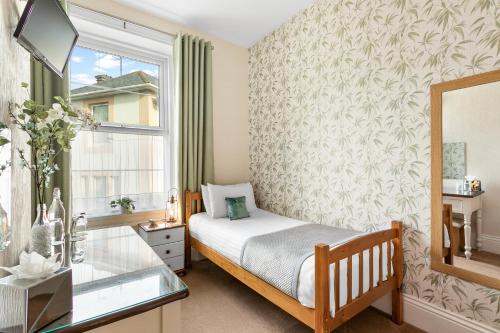 um pequeno quarto com uma cama e uma janela em Kings Lodge em Torquay