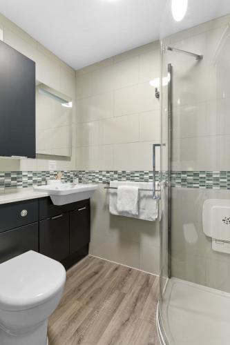 a bathroom with a toilet and a sink and a shower at Kings Lodge in Torquay