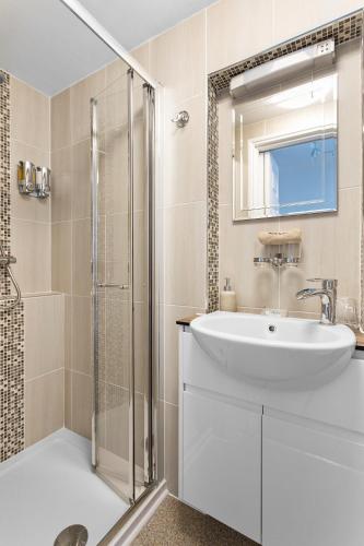 a white bathroom with a sink and a shower at Kings Lodge in Torquay