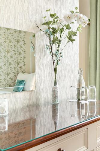 a vase with white flowers on a counter with glasses at Kings Lodge in Torquay