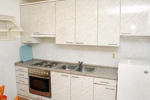 una cocina con armarios blancos y fregadero en Apartments by the sea Zavode, Omis - 1048, en Lokva Rogoznica