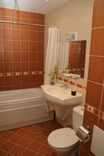 a bathroom with a toilet and a sink and a tub at Hotel Real in Plovdiv