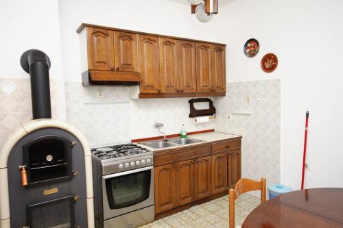 a kitchen with wooden cabinets and a stove and a sink at Apartments by the sea Privlaka, Zadar - 666 in Privlaka