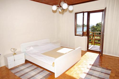 a bedroom with a white bed and a large window at Apartments by the sea Privlaka, Zadar - 666 in Privlaka