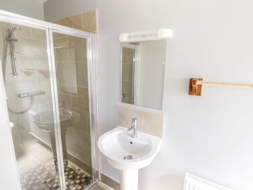 La salle de bains blanche est pourvue d'une douche et d'un lavabo. dans l'établissement The Visiting House, à Dunmore