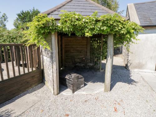 a wooden pergola with a table and a grill at The Visiting House in Dunmore