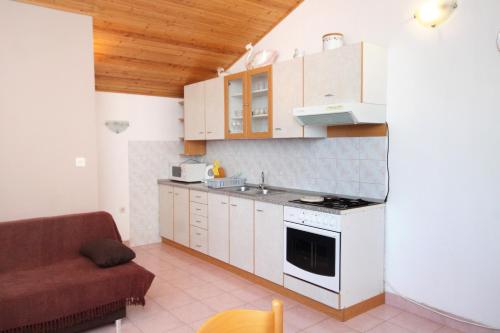 a small kitchen with white cabinets and a couch at Apartments by the sea Kali, Ugljan - 837 in Kali