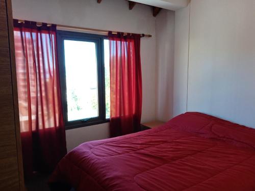 1 dormitorio con 1 cama y una ventana con cortinas rojas en LA CASITA DE ALEX en San Carlos de Bariloche