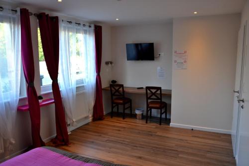 a bedroom with red curtains and a table and chairs at Hôtel Restaurant La Couronne in Roppenheim
