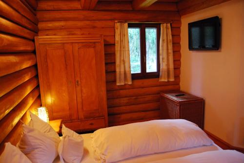 una camera con un letto in una baita di tronchi di Boróka Apartmanházak - Kakukk House a Velem