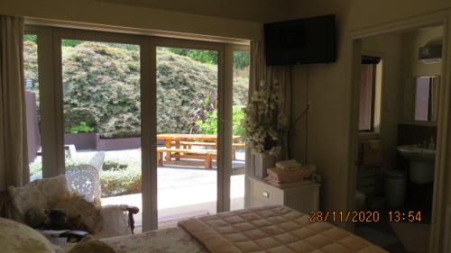 a bedroom with a sliding glass door to a patio at Bush Line Lodge in Motueka