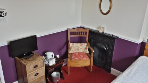 a room with a chair and a fireplace and a tv at The Ship Inn in Fordingbridge