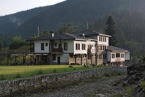a large white house with a stone wall at Family Hotel Arkan Han in Trigrad