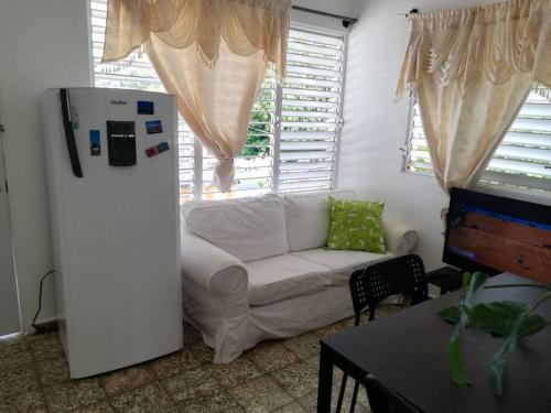 a living room with a white couch and a refrigerator at Studio Centrally located, 50 mts from El Malecón. in Santa Bárbara de Samaná
