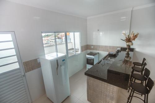 uma cozinha com um balcão, um frigorífico e cadeiras em Souza Reis Apart - Unidade 1 em São Tomé das Letras