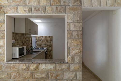 a kitchen with a stone wall with a mirror at Apartments by the sea Maslinica, Solta - 775 in Grohote