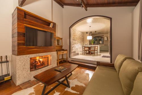 a living room with a fireplace and a television at Vila Suzana Parque Hotel in Canela