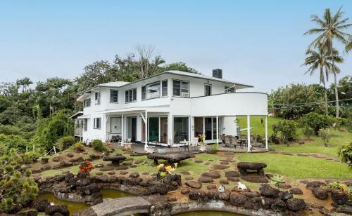 a white house with a stone bridge in the yard at Hilltop Legacy Vacation Rental in Hilo