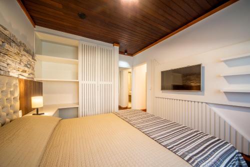 a bedroom with a bed and a tv on the wall at Vila Suzana Parque Hotel in Canela