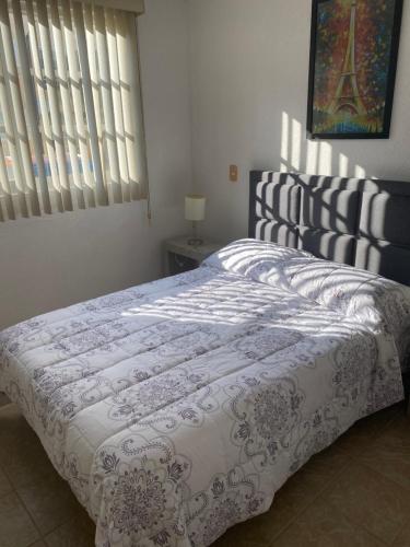 a bedroom with a bed with a comforter on it at Renta de departamento en Acapulco Diamante in Acapulco